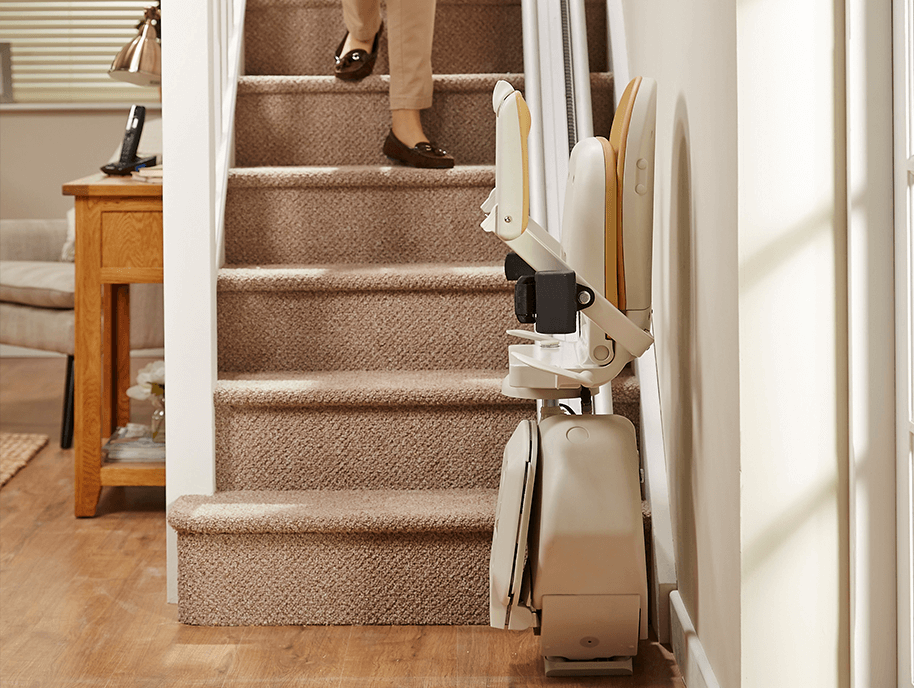 An AMS stairlift folded away at the bottom of the stairs