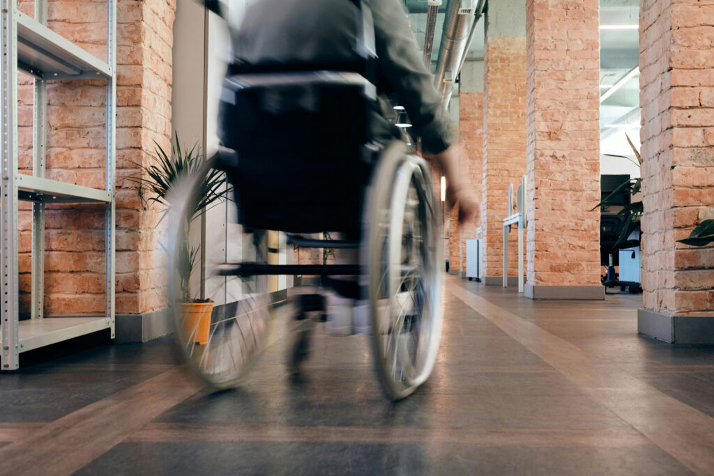 Man rolling wheelchair through an office